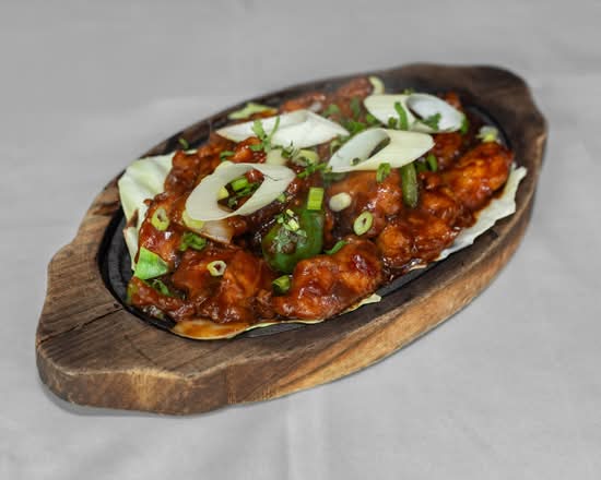 Slow-cooked lamb curry garnished with red onion and coriander at Copper Chimney Winnipeg