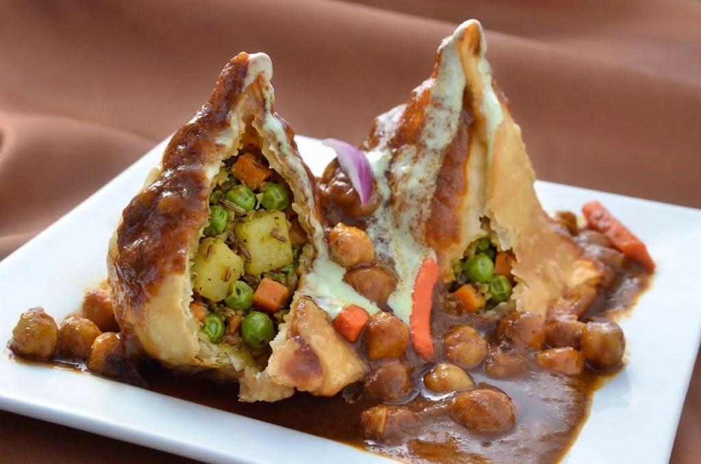 Samosa chaat topped with chickpeas, onions and mint chutney at Copper Chimney Winnipeg